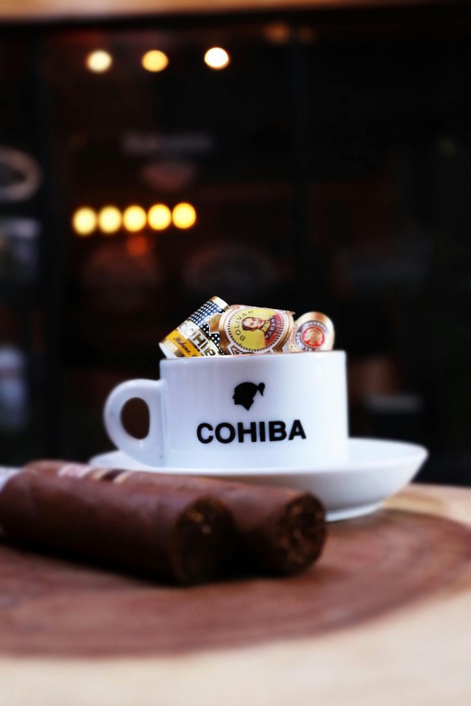 Close-up of Cohiba cup filled with cigar bands on a wooden surface, perfect for cigar enthusiasts.